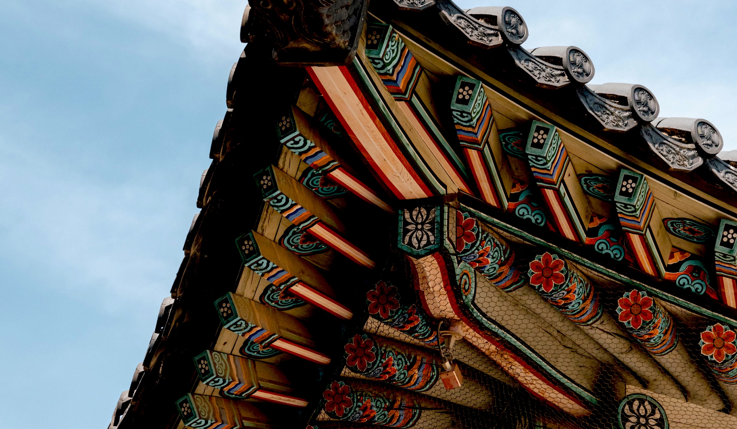 Close-up of an ornate, colourful temple roof against a clear blue sky.
