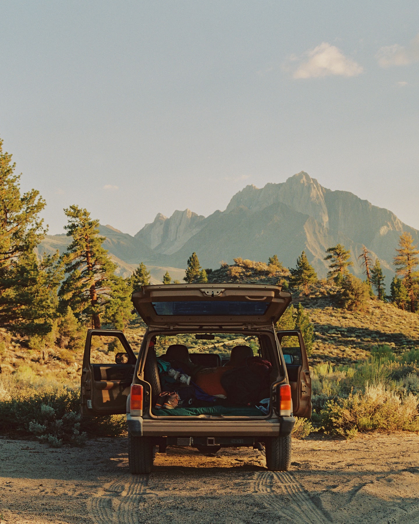 Camping-car garé dans une vallée montagneuse, avec les portes arrière ouvertes.