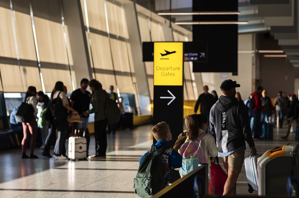 Reizigers met handbagage lopen richting een gate op een luchthaven