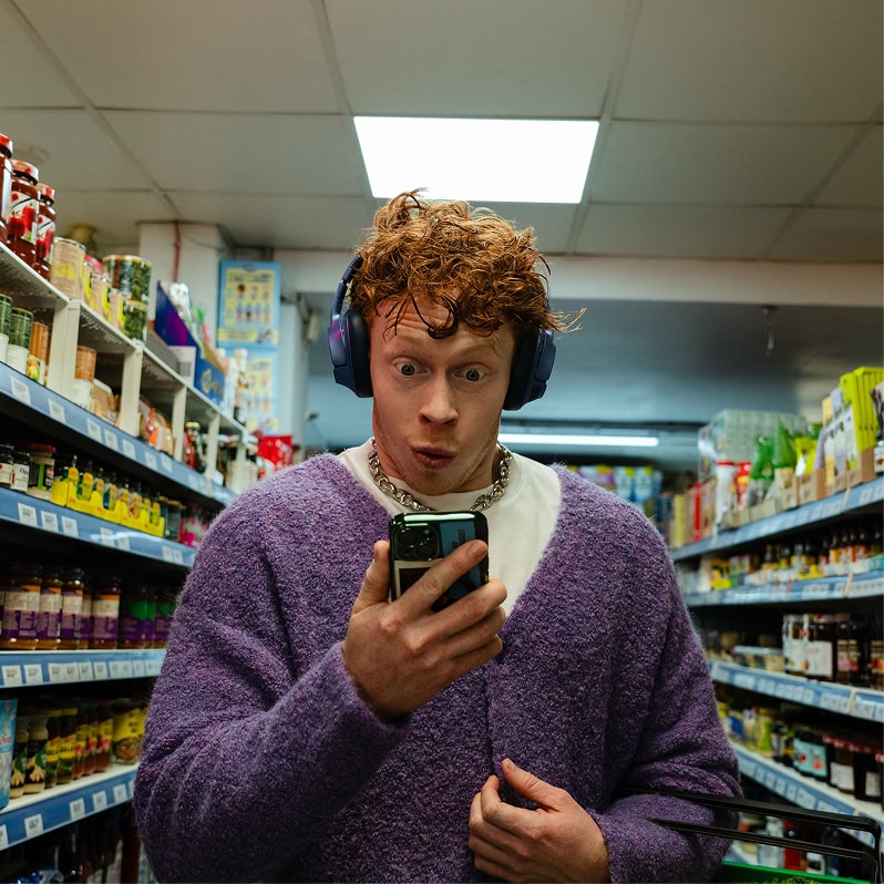 Person checking their phone in a supermarket aisle
