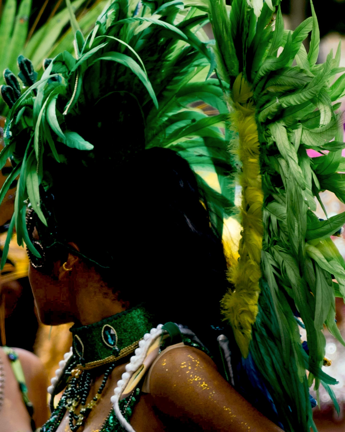 Artiste de carnaval portant un costume à plumes vert vif.