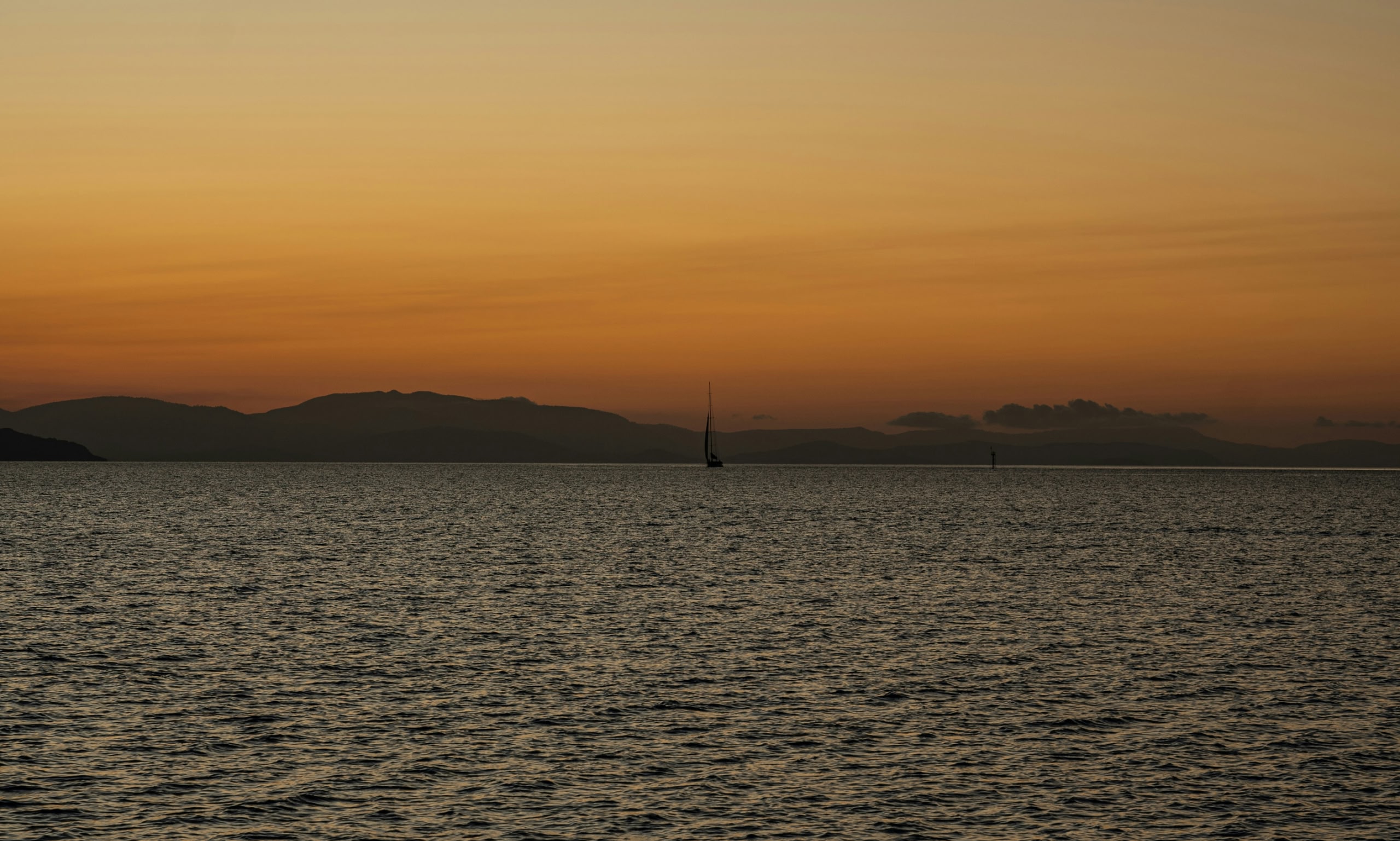 Voilier sur une mer calme au coucher du soleil.