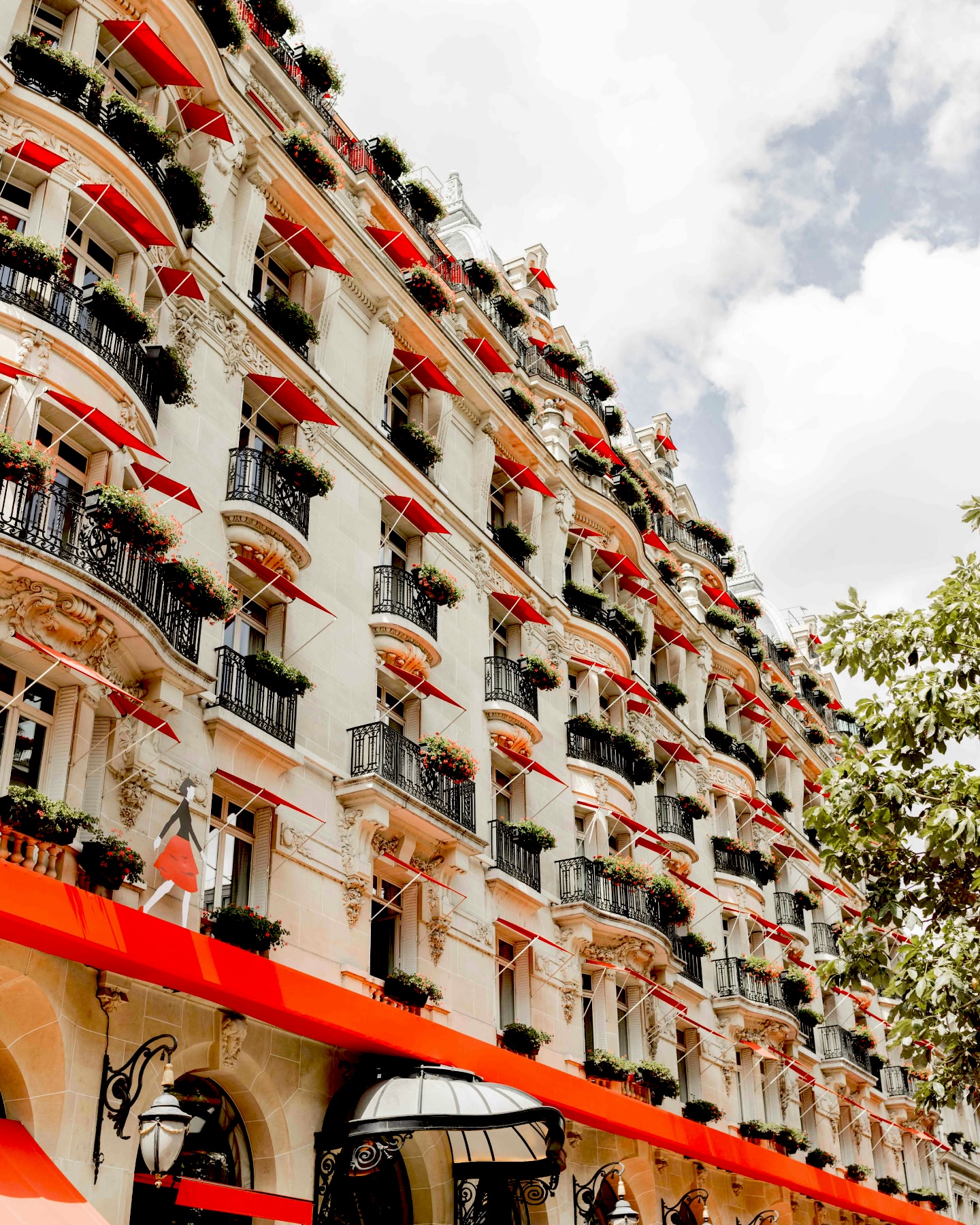 Prachtvolles Hotel mit roten Markisen, Balkonen und blumengeschmückten Blumenkästen.