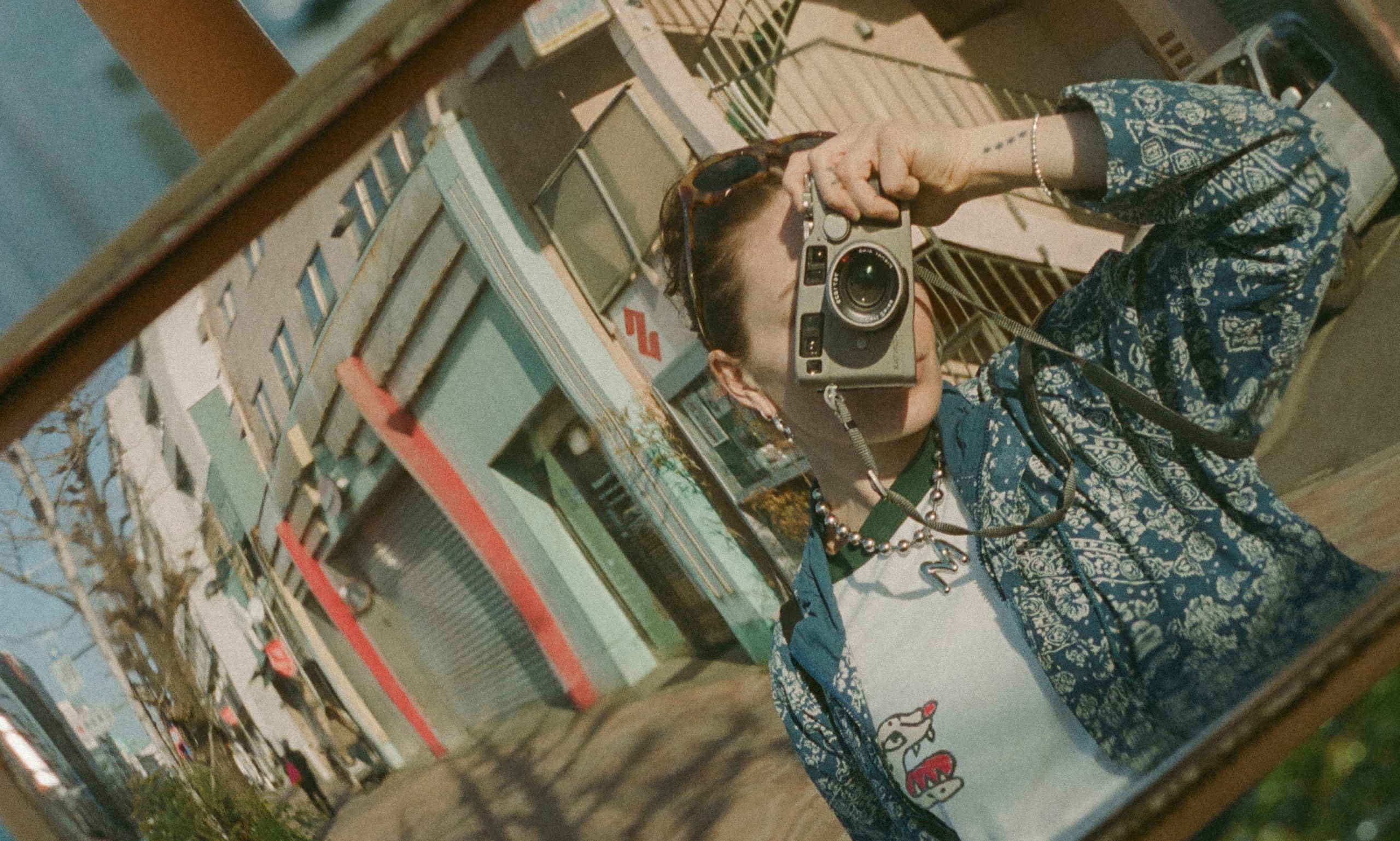 Personne prenant une photo avec un appareil photo vintage dans une rue de la ville.