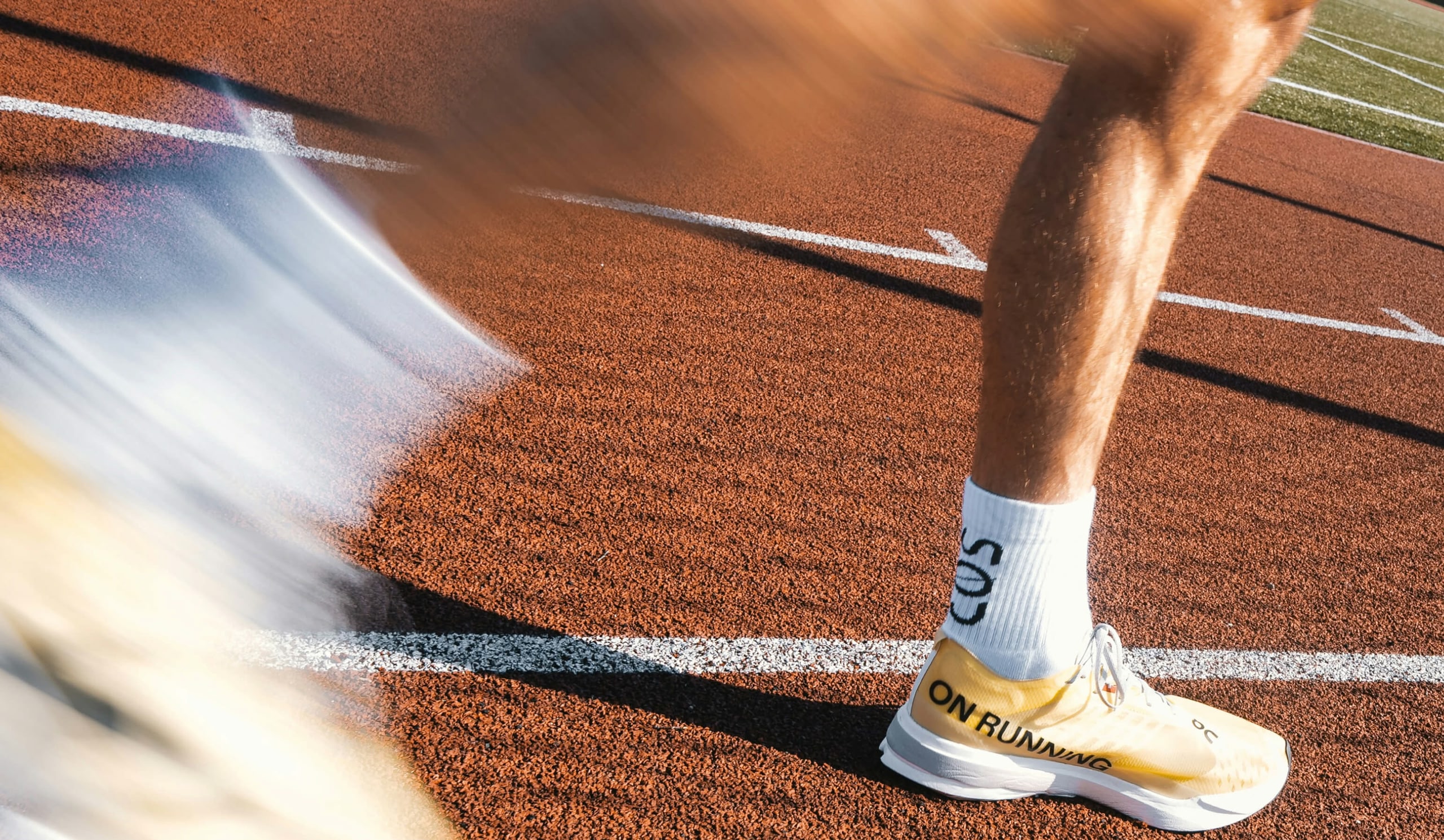 Close-up of a runner wearing yellow trainers on an outdoor running track