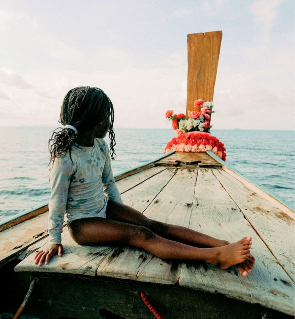 قوارب ذات ذيول طويلة (Longtail boats) تطفو على مياه فيروزية، مع جزيرة خضراء وارفة في كرابي، تايلاند.