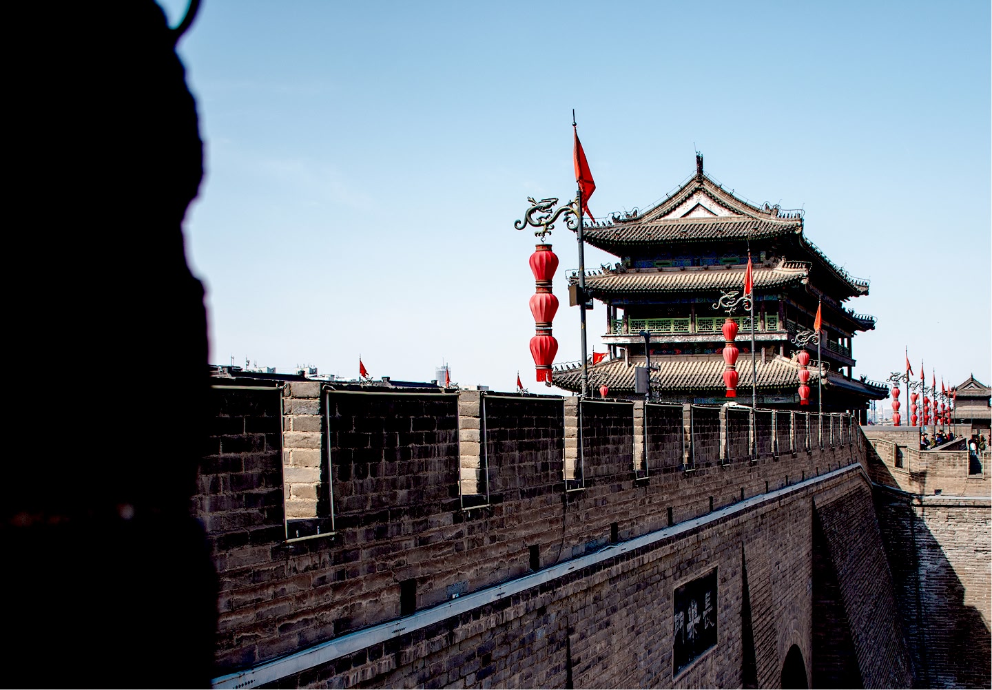 Traditionelle chinesische Stadtmauer und ein Wachturm, geschmückt mit roten Laternen.