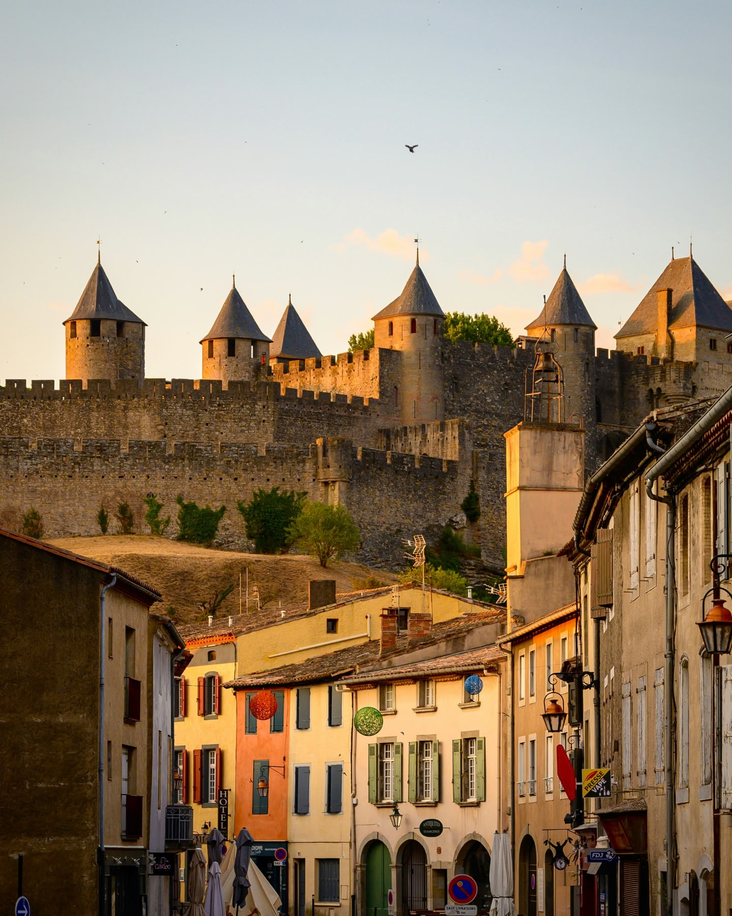 Mittelalterliche Festung mit Blick auf eine historische Stadt bei Sonnenuntergang.