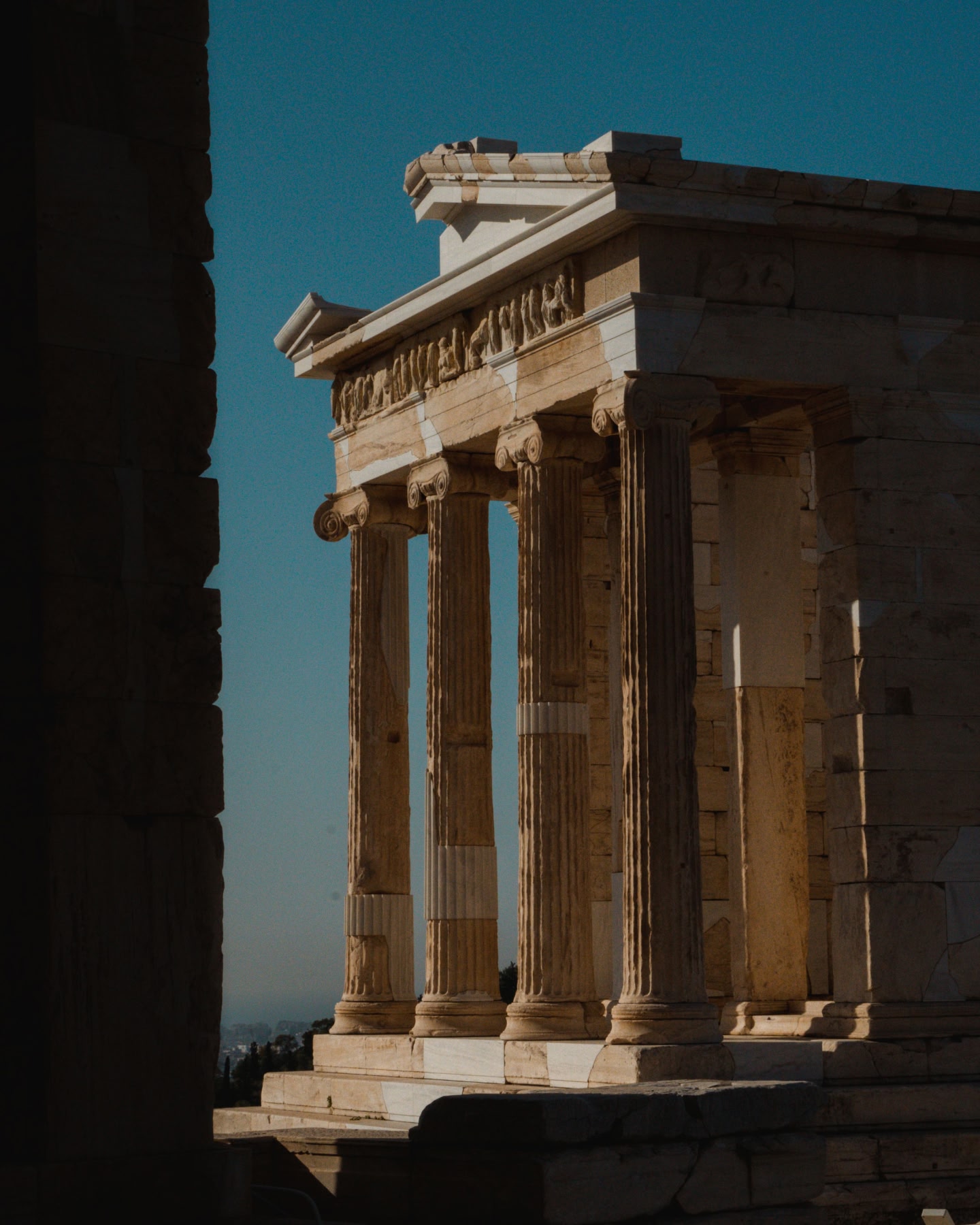 Antiker griechischer Tempel mit Marmorsäulen unter einem klaren, blauen Himmel.