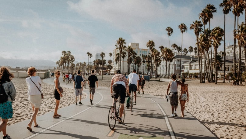 Personen fietsen over een pad langs het strand
