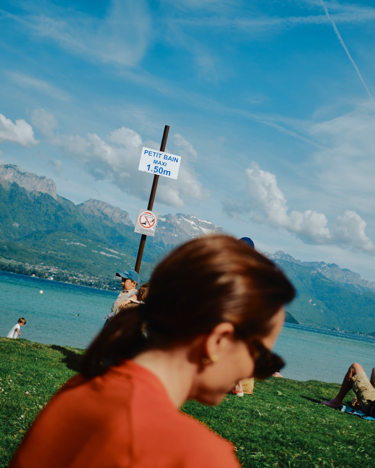 People relaxing by a lakeside with mountains in the background.