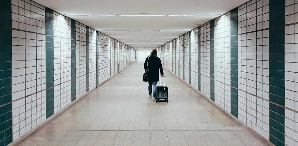Reiziger met handbagage loopt door een tunnel op een luchthaven
