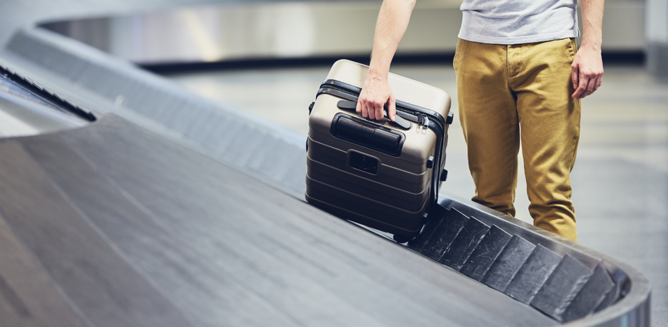 Reiziger haalt koffer van de bagageband op de luchthaven