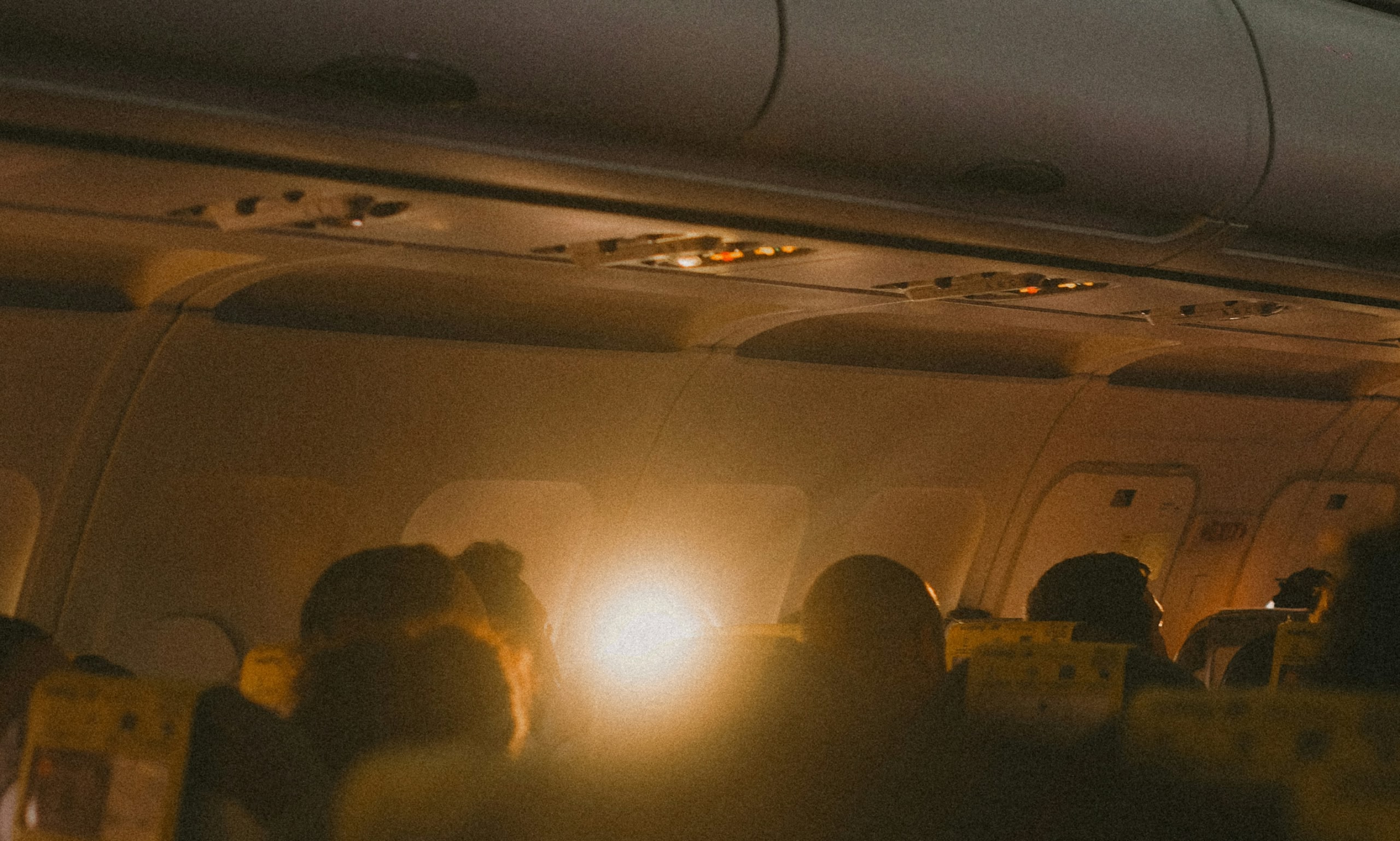 Passagers assis dans la cabine d’un avion au coucher du soleil.