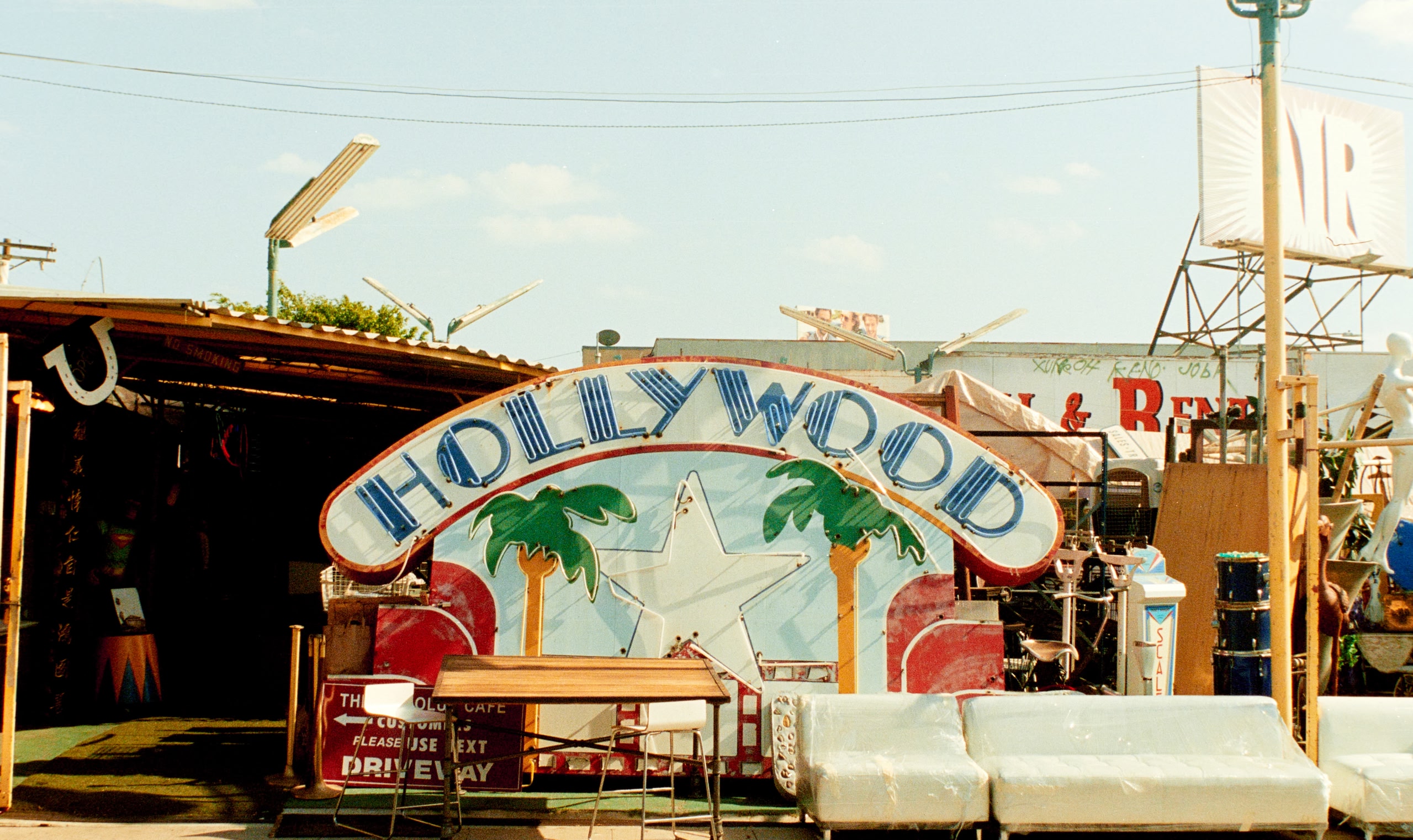 Vintage-Schild mit der Aufschrift „Hollywood“ zwischen Marktständen und Retro-Möbeln.