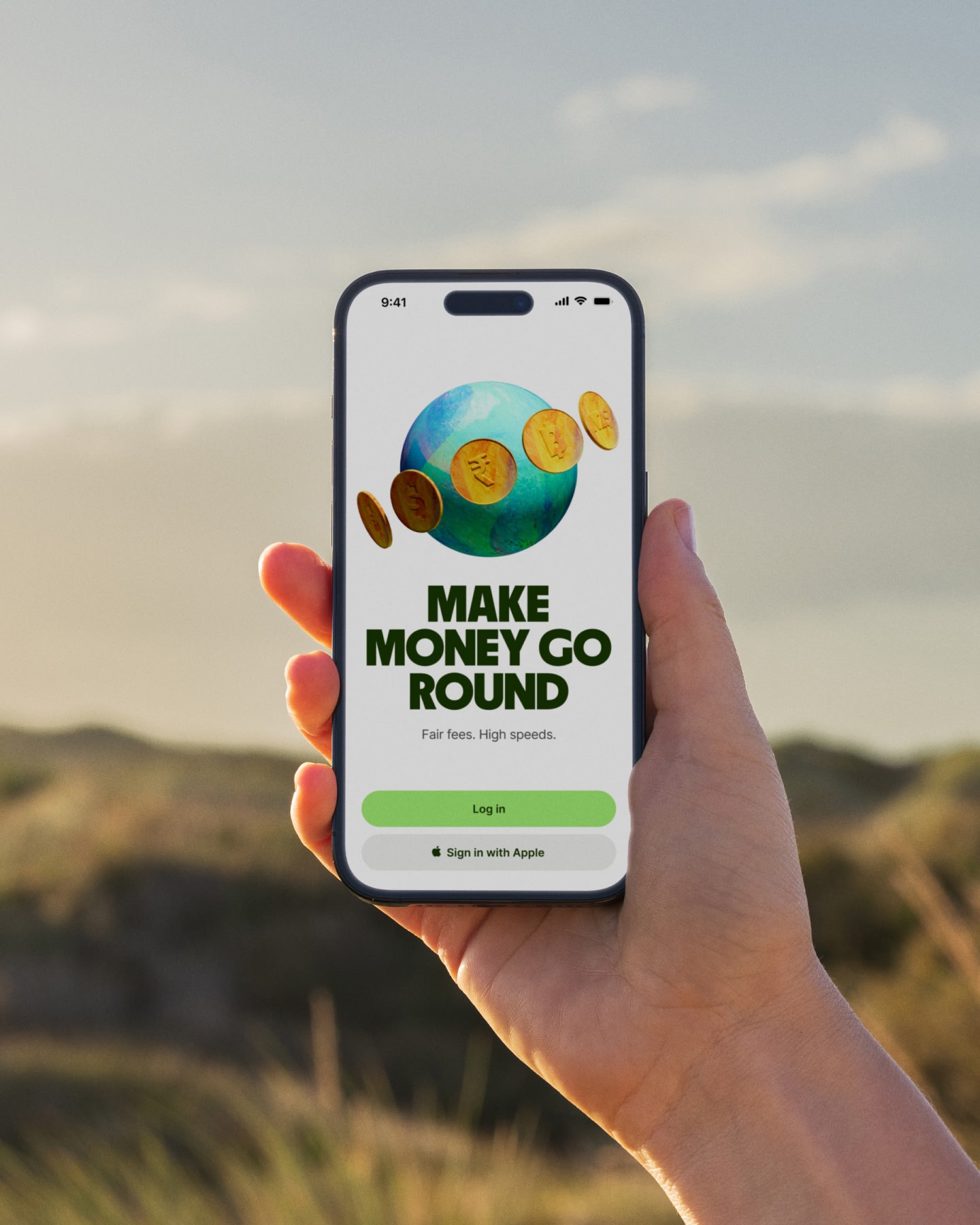 Hand holding a smartphone outdoors against a blurred landscape.