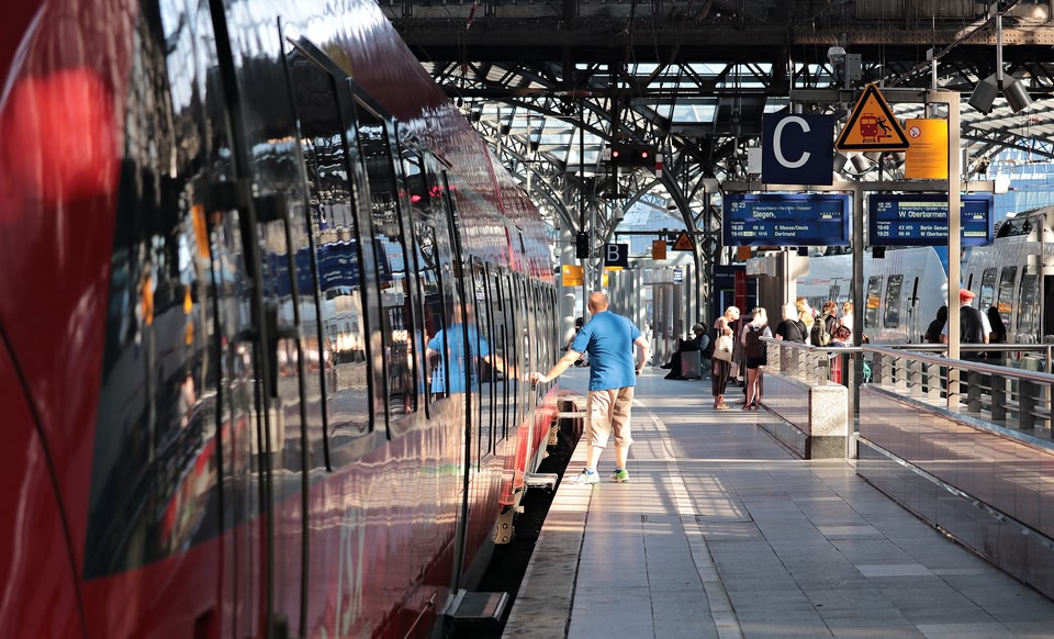 Trein op station met reiziger die op de knop drukt om de deuren te openen