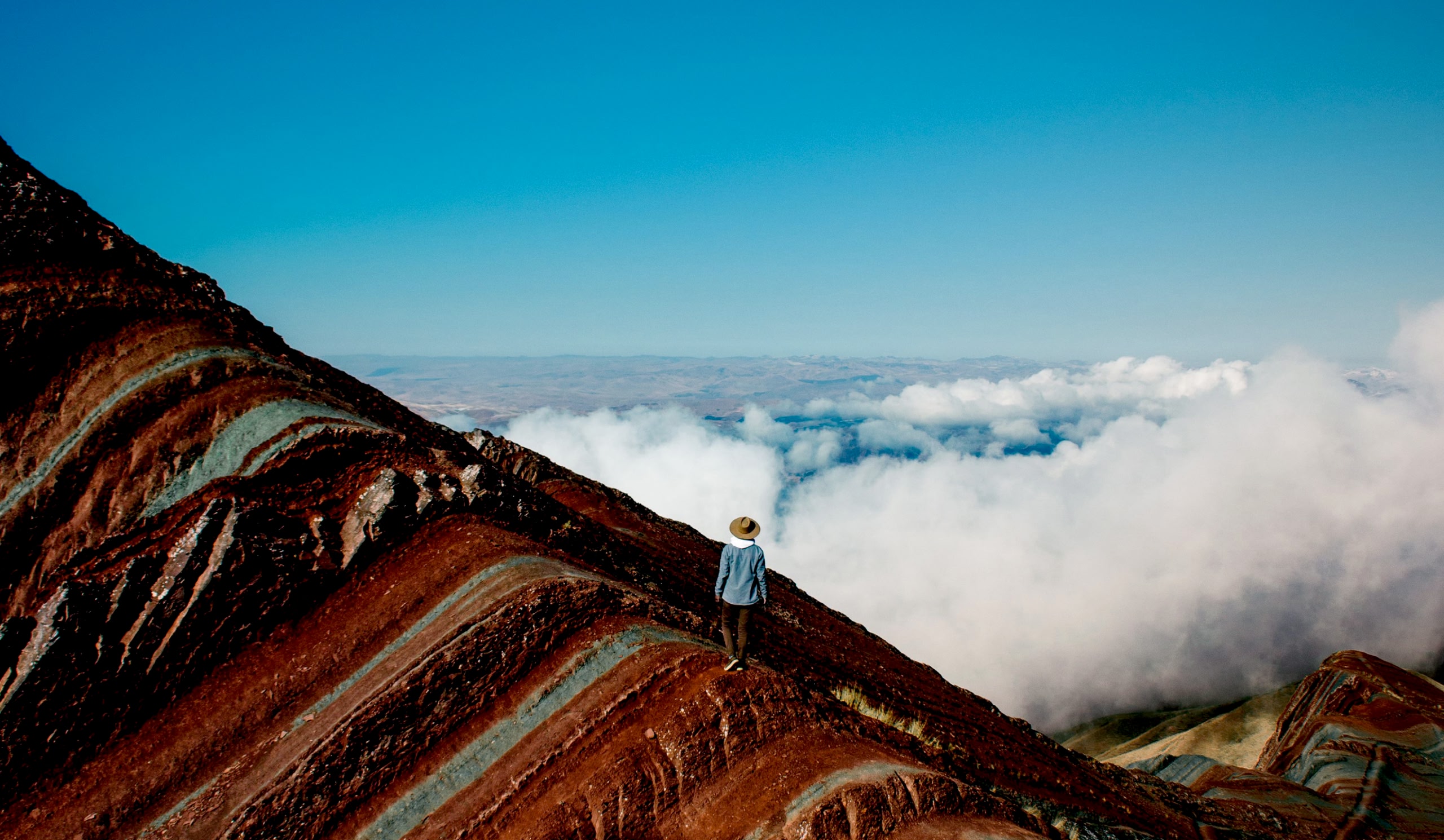Wanderer, der auf einem farbenfrohen Bergkamm über den Wolken steht.