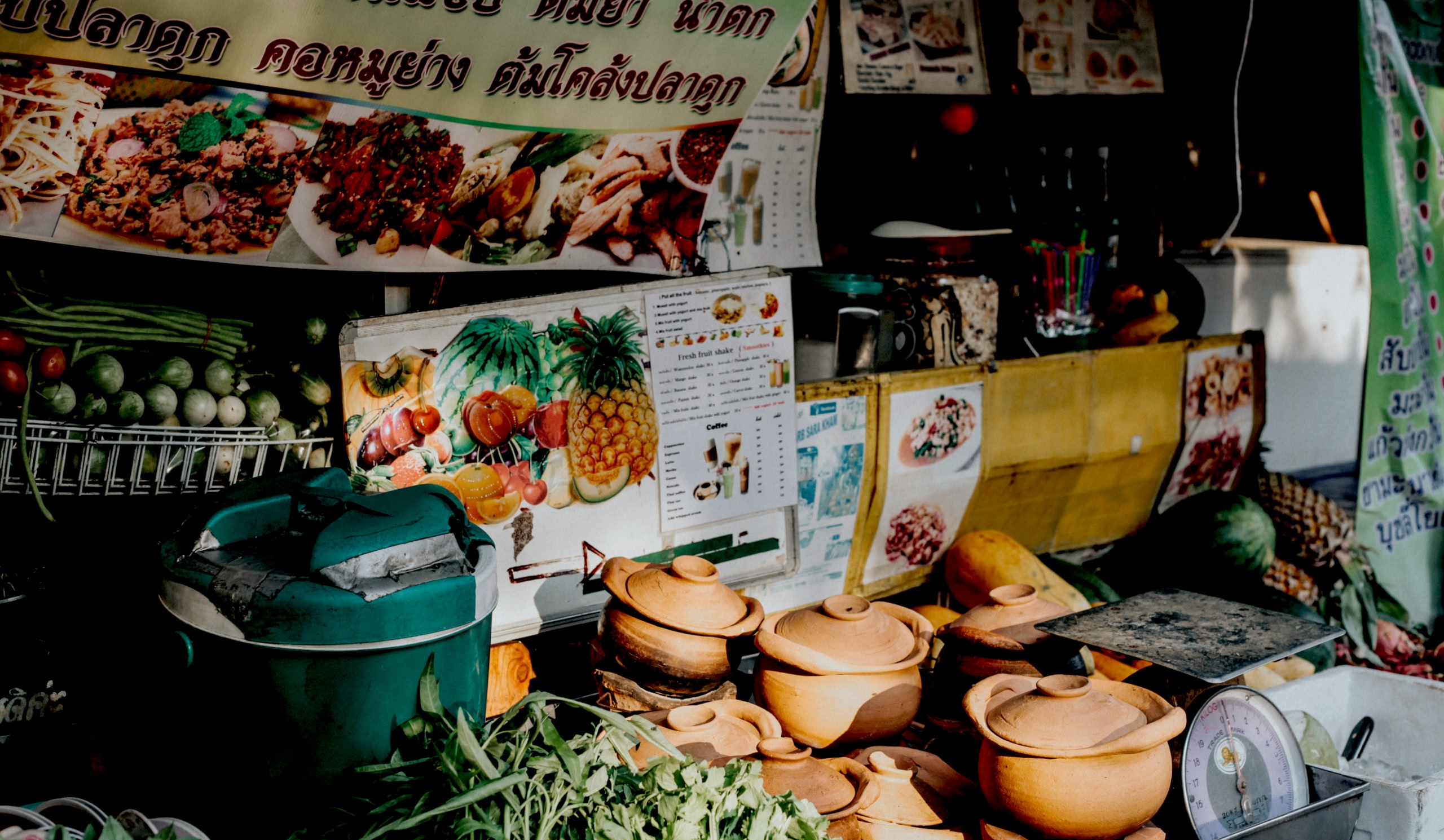 Traditional market stall selling fresh produce and clay pots.