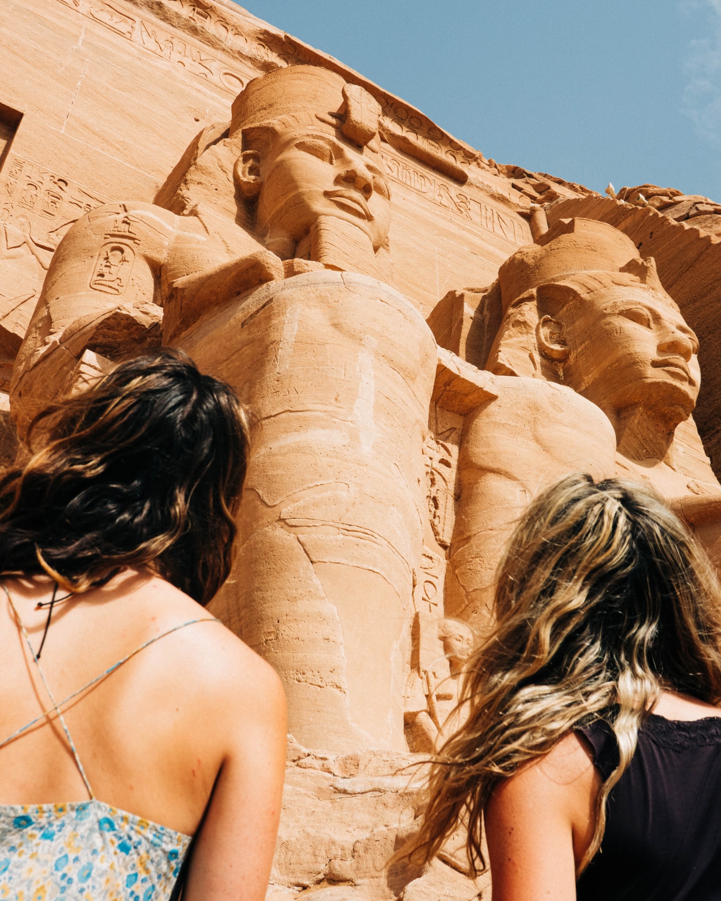 Besucher, die zu den kolossalen Statuen von Abu Simbel hinaufschauen.