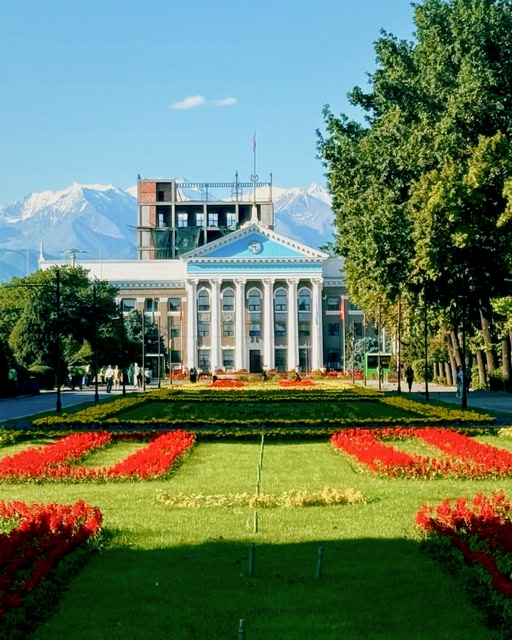 Gebäude in Bischkek mit Garten und Berglandschaft im Hintergrund