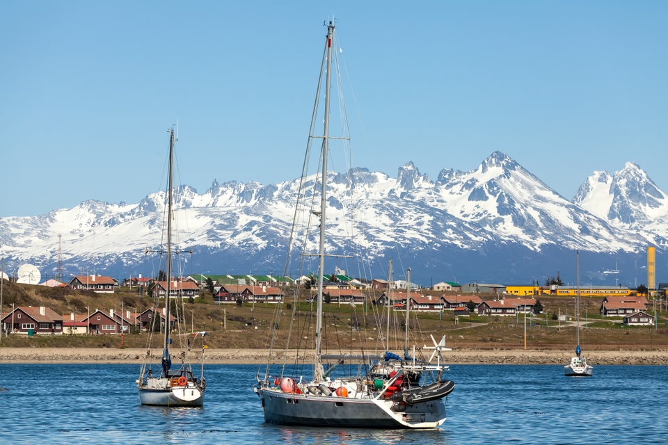 Montanhas com neve e barco em Ushuaia, lugar ideal para conhecer em viagens em janeiro