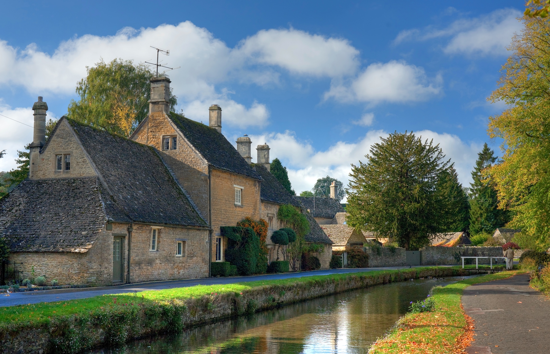 Still river stretching into the distance lined by traditional English buildings and grassy banks