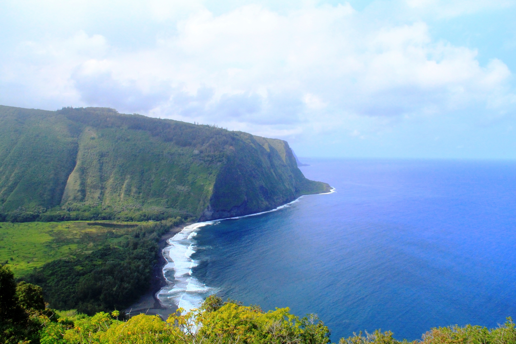 blue waves meet a green mountain from hawaiian glampsite
