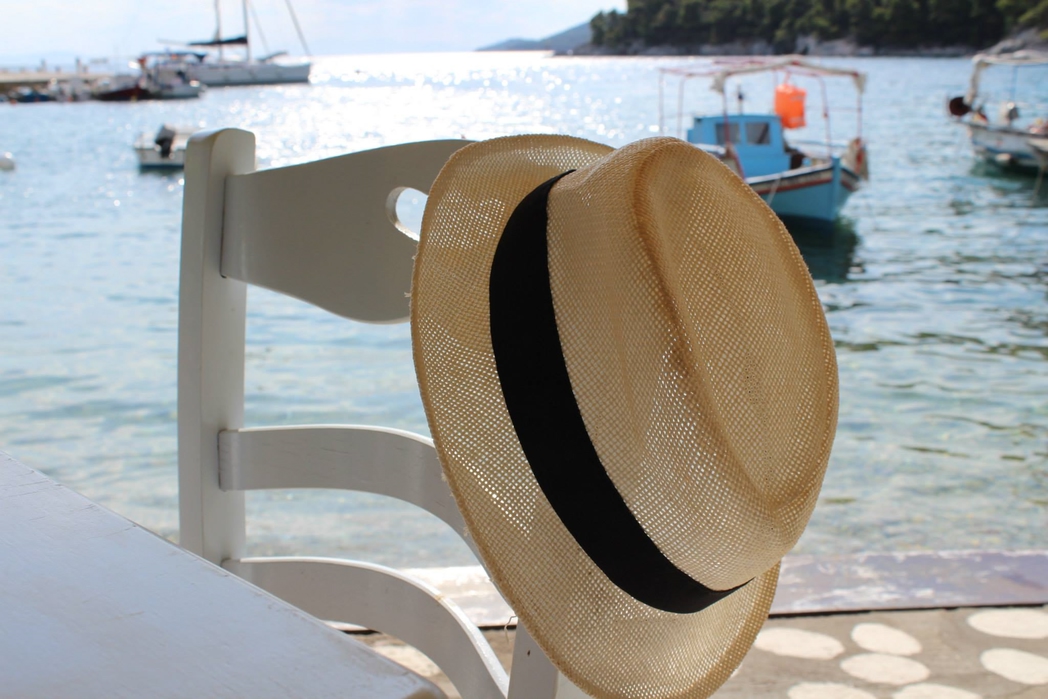 Kαπέλο κρεμασμένο σε καρέκλα δίπλα σε λιμάνι με καϊκια