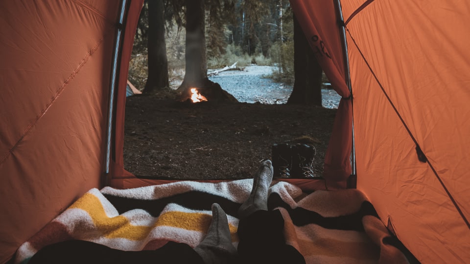 Inside a n orange tent with blankets inside