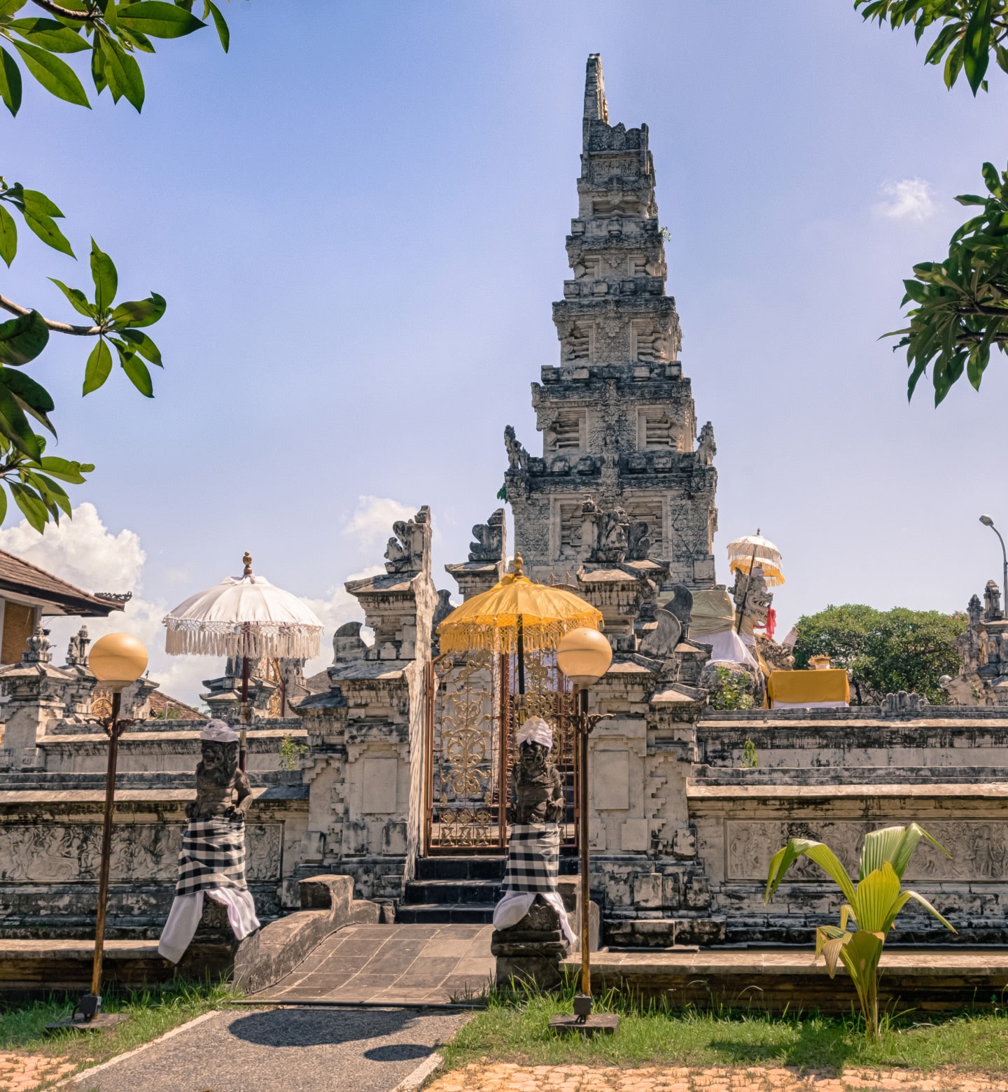 A traditional Balinese temple with parasols and stone carvings in Denpasar, Indonesia.