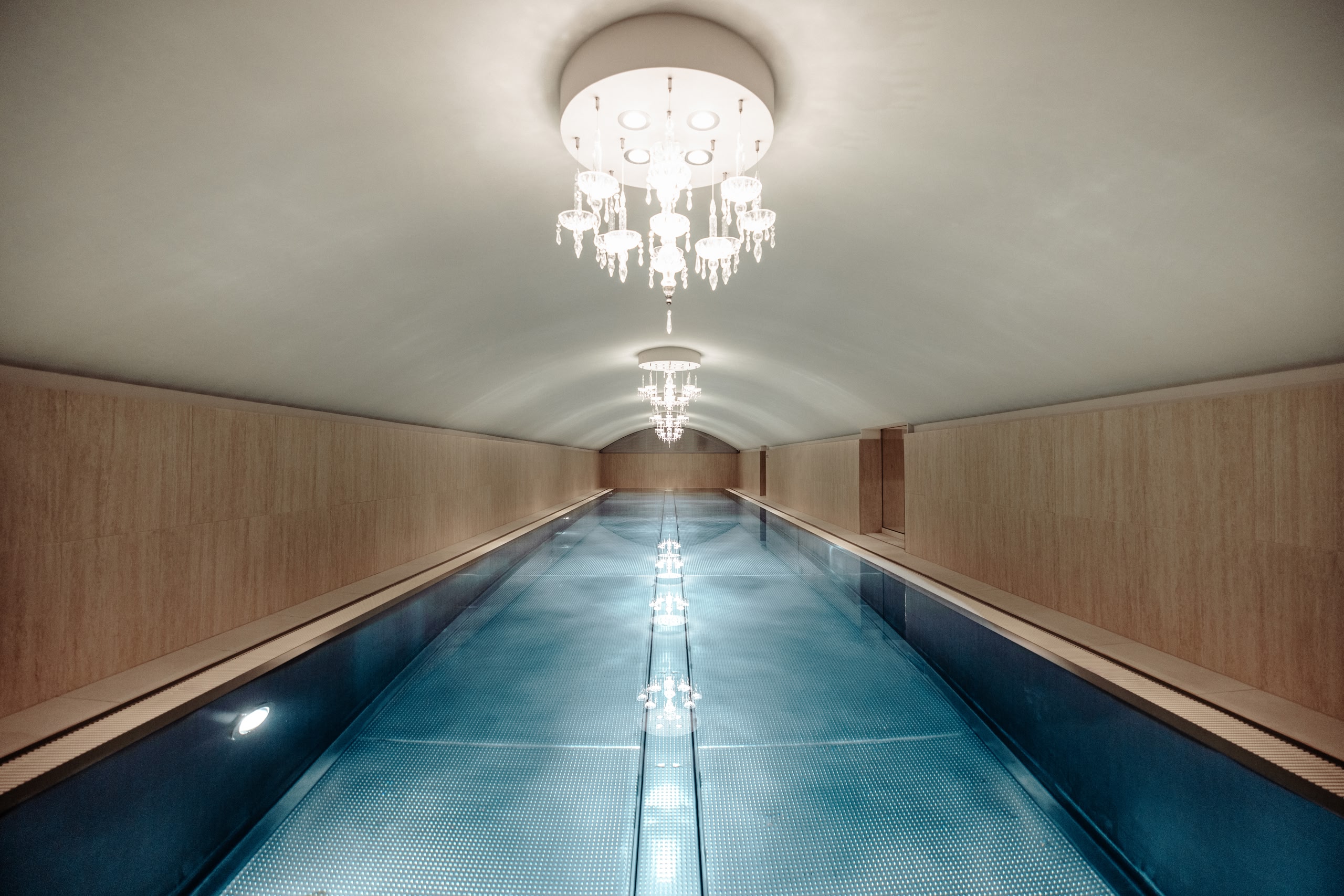 Uma longa piscina no porão do Sans Souci Wien com lustres pendurados acima.