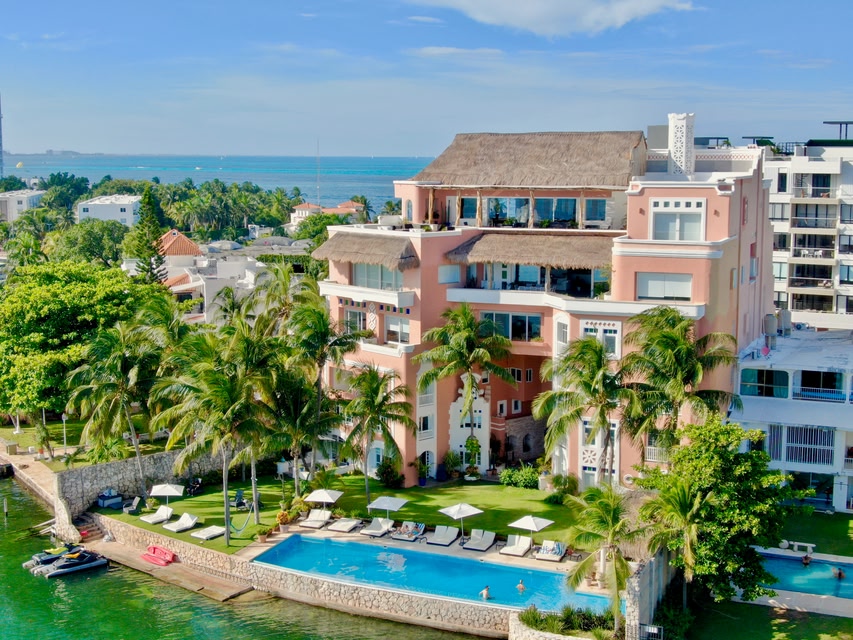 multi-story hotel with a pool, with a body of water in the foreground and background