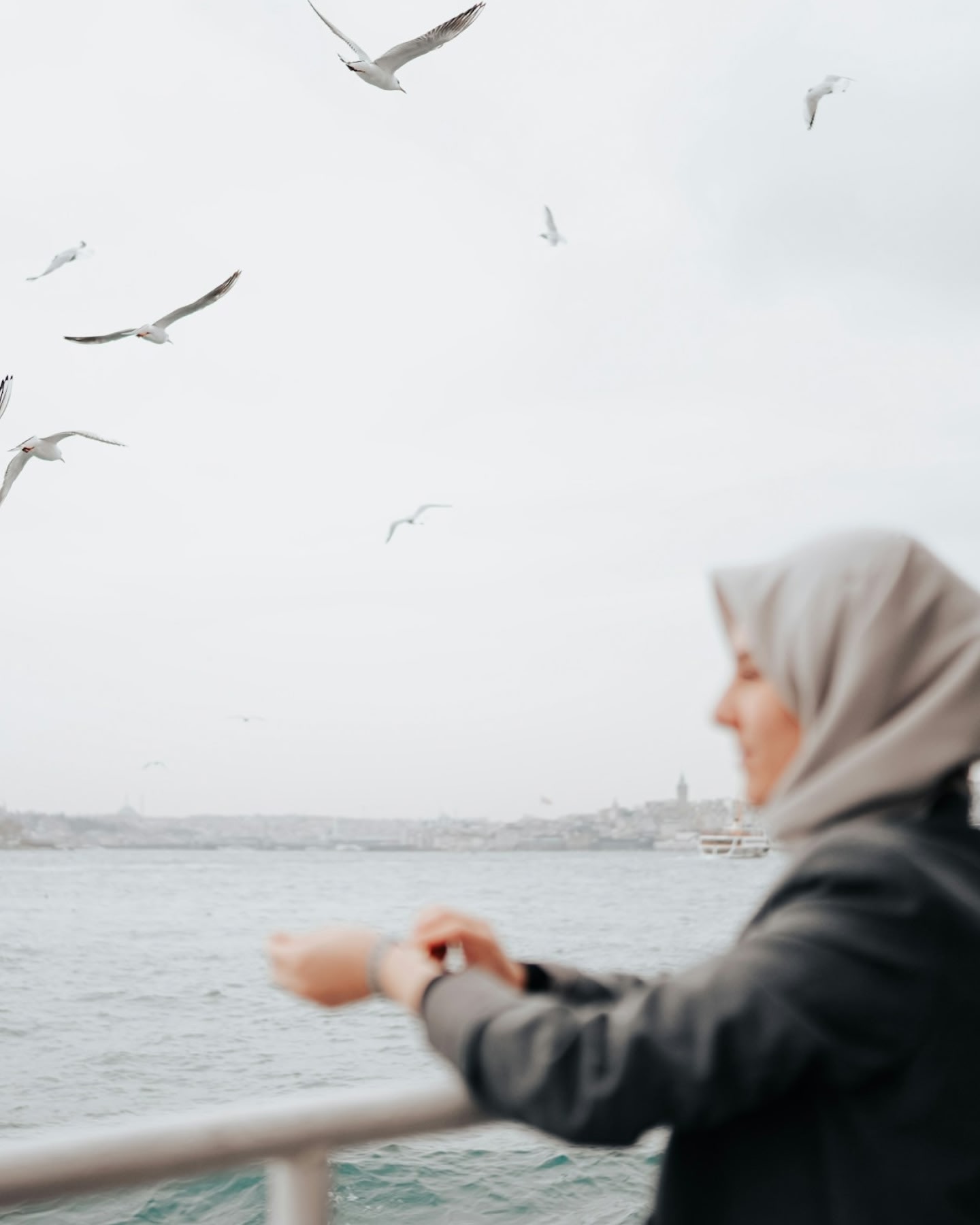 امرأة تشاهد طيور النورس تحلق فوق البحر.