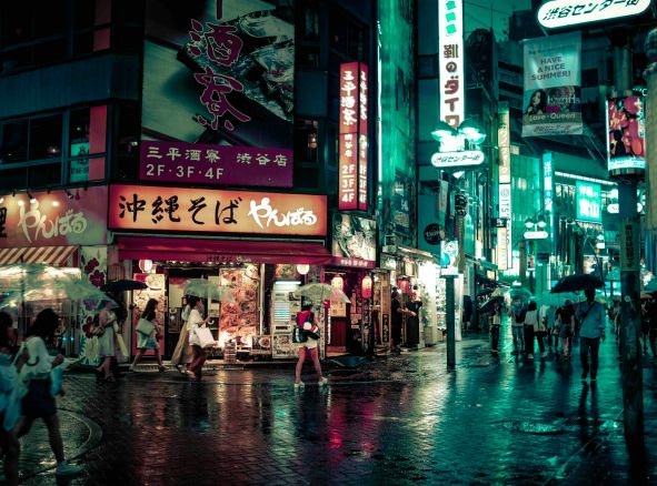 An image of a Japanese street with people walking during night time