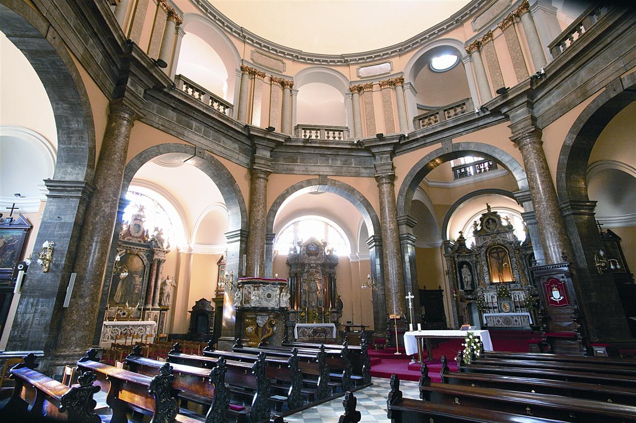 Photo shows the interior of Rijeka Cathedral in Croatia, showing the ornate interior design of marble arches and wooden pews, with a domed ceiling,