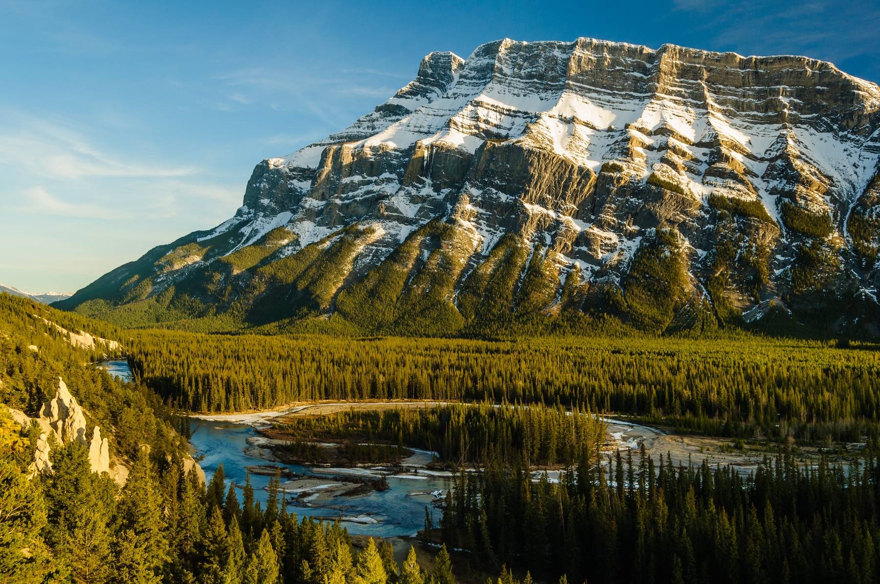 mountain range behind a river and forest 