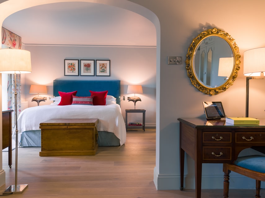 Bedroom at Chewton Glen Hotel. Colourfully decorated bed in background, desk in foreground.
