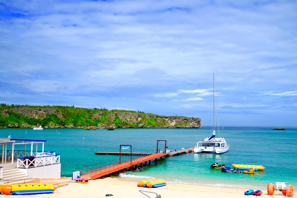 Schooner boat launching from the white sandy beach into the turquoise waters of  Okinawa, Japan