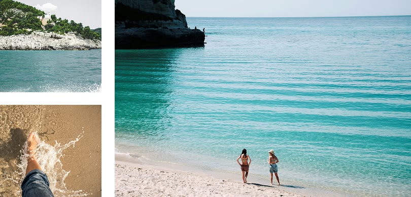 una spiaggia con acqua turchese cristallina, delle scogliere rocciose e delle persone che passeggiano a mare