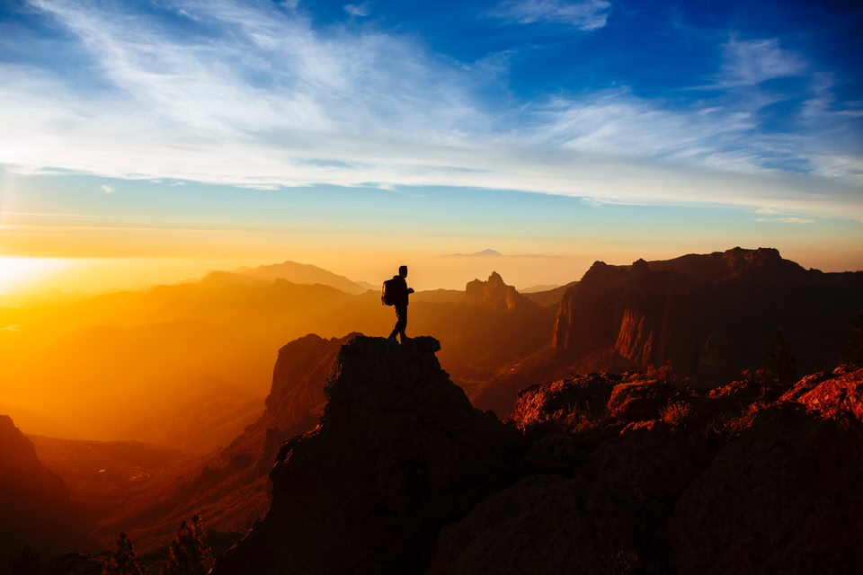 homem de costas apreciando a vista do topo de uma montanha - trilhas no Brasil