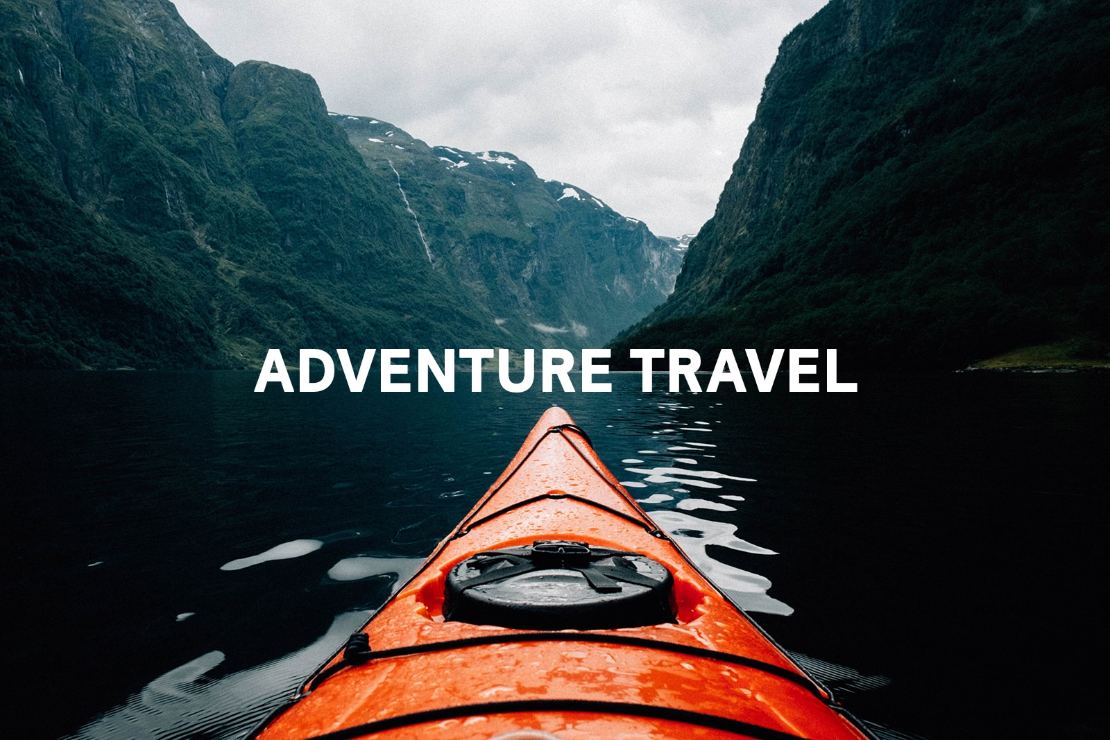 Tip of red kayak on the water between two cliffs with the words "adventure travel" in the middle of the photo