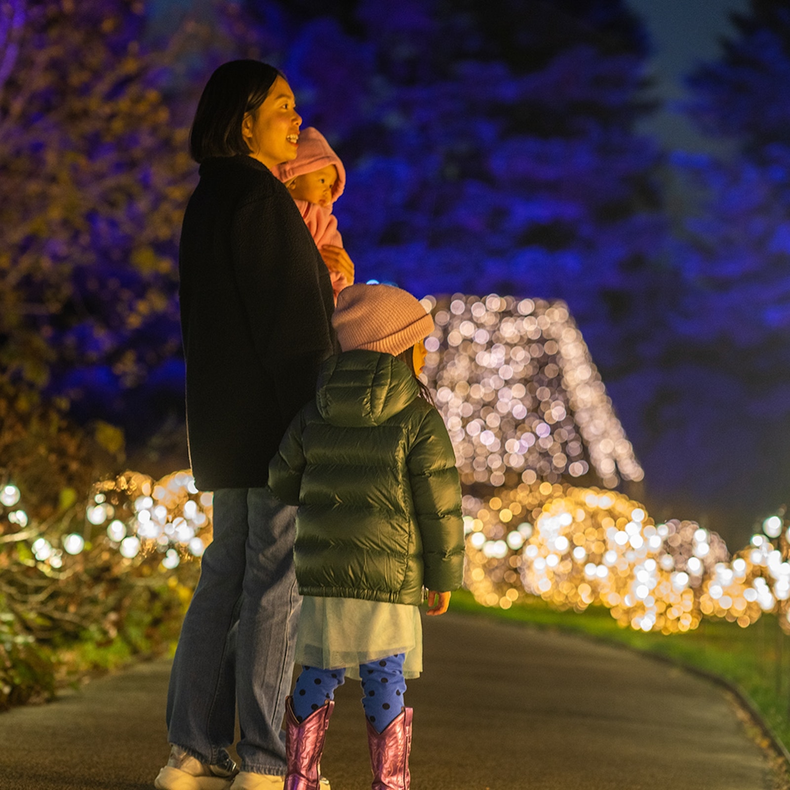 A mother and two children watch the holiday lights at the New York Botanical Gardens.
