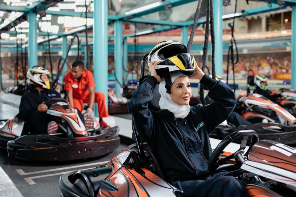 Eine Frau in einem Gokart in der Ferrari World in Abu Dhabi, die ihren Helm abnimmt.
