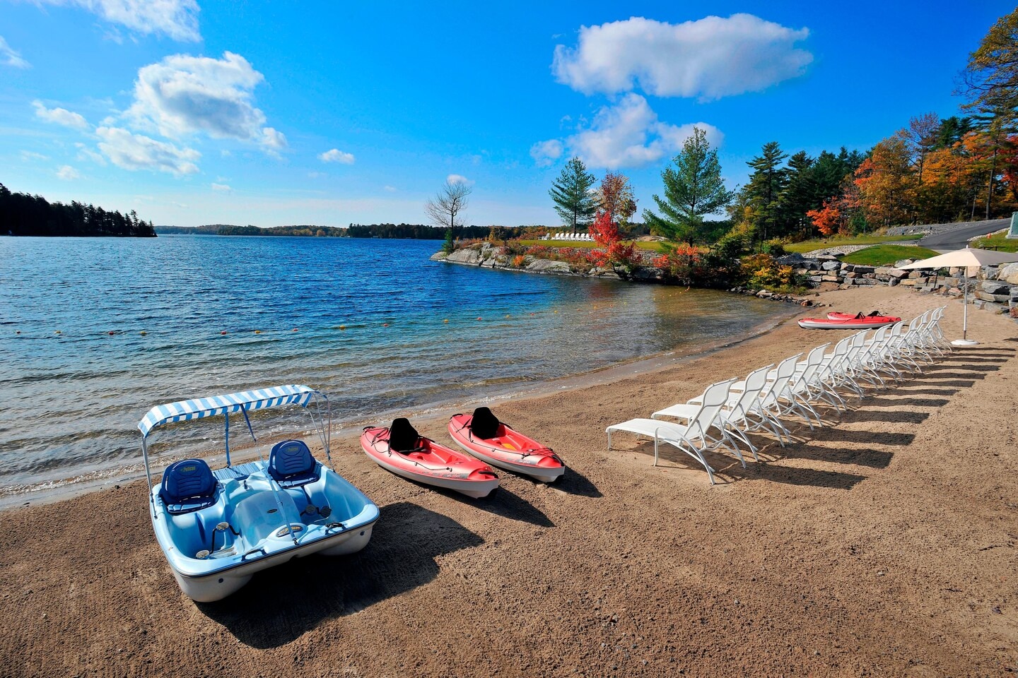 Best beach hotel views at J W Muskoka with kayaks, paddle boards and lounging chairs by the water