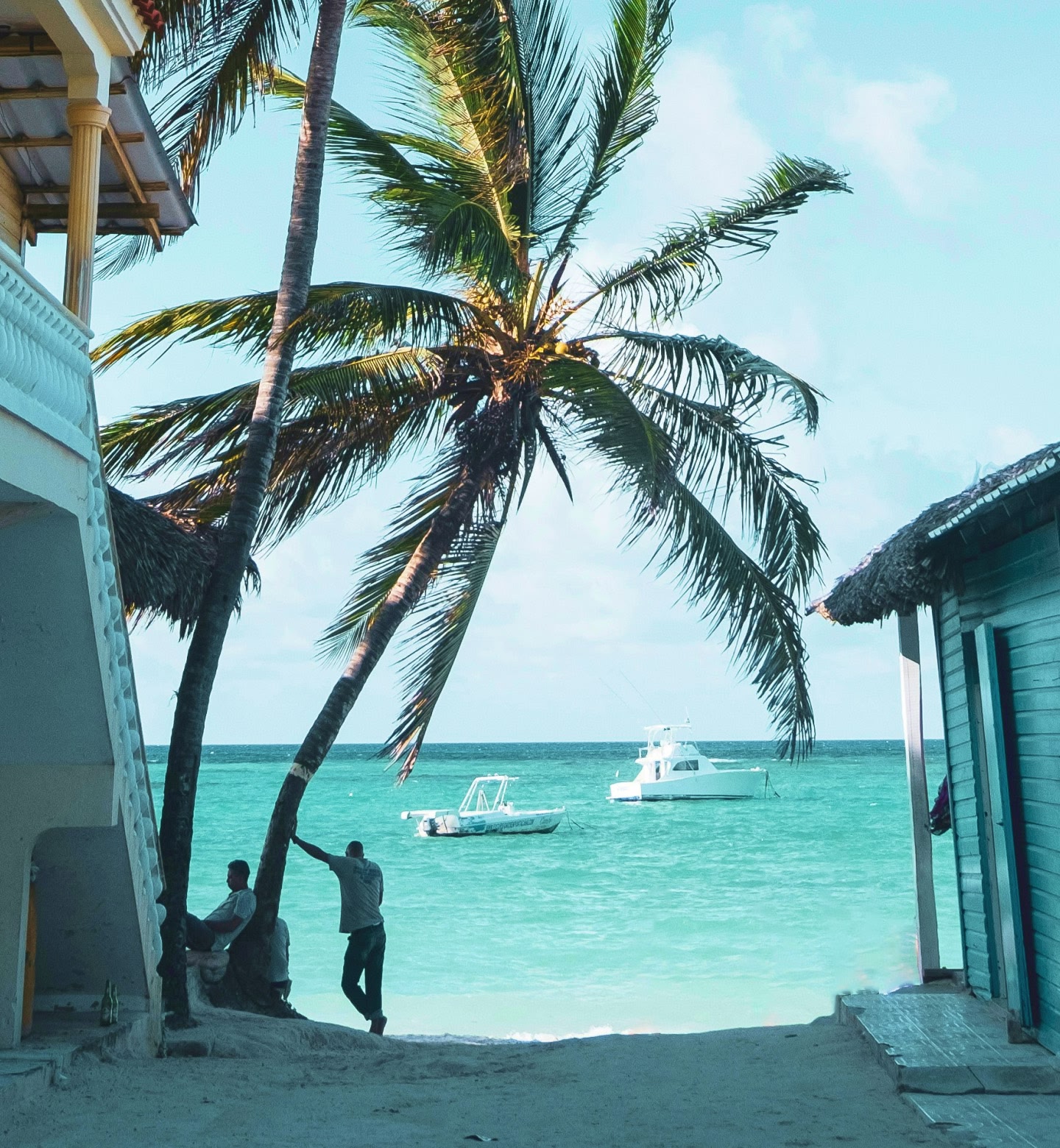 Palmeiras ao lado do oceano azul-turquesa com barcos na água em Punta Cana, República Dominicana.