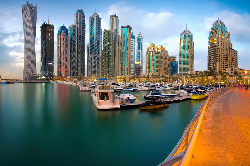 A view across the Emirates Marina in Dubai with the promenade, water and boats and skyscrapers.
