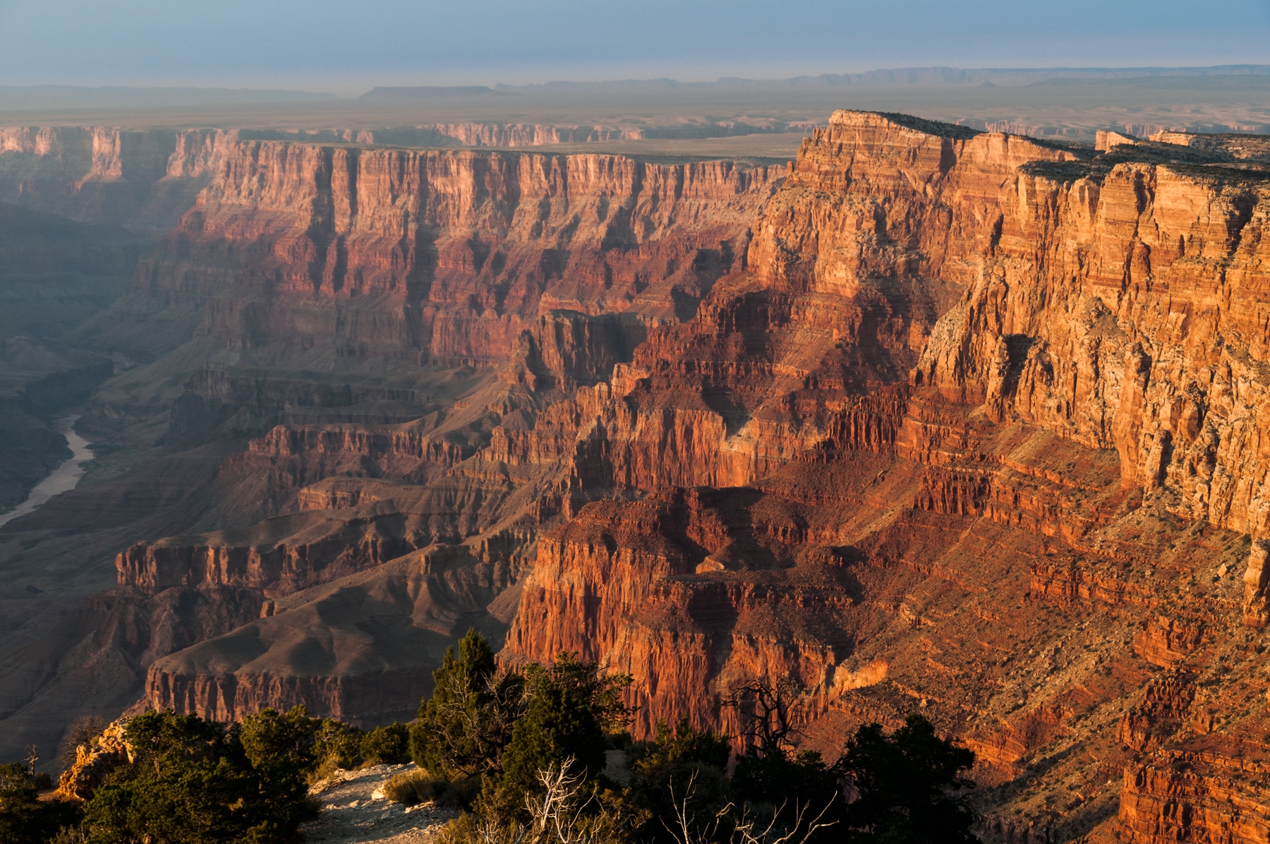 the rusty red walls of a very deep canyon being illuminated by sunset.