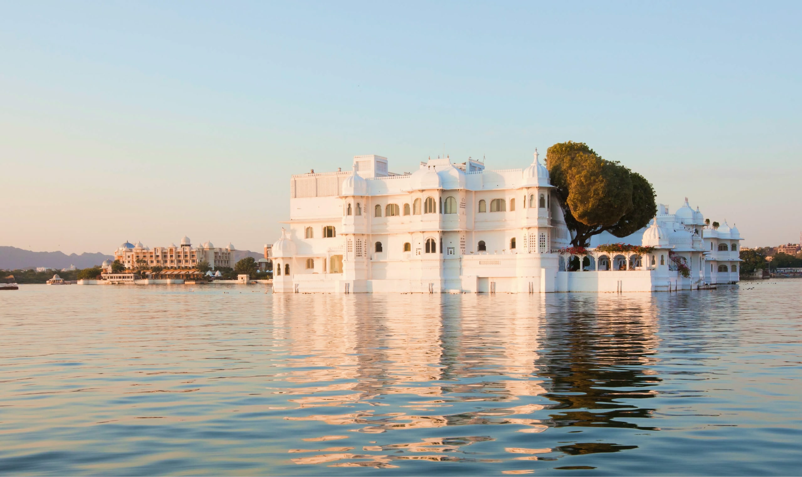 Large white building surrounded by water with other buildings in the background