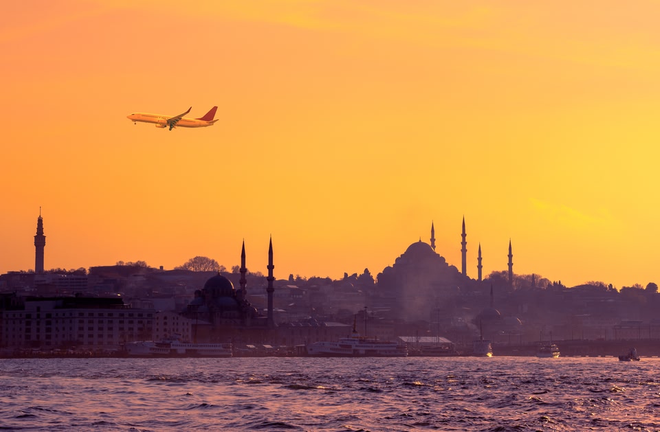 Travel to Istanbul on passenger transport in Turkey. Sunrise in golden colors with soft light effect. Turkish landmarks - panoramic cityscape of Istanbul with silhouette of mosques on seaside.